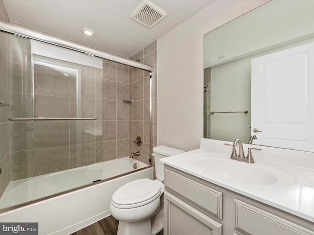 full bathroom featuring toilet, vanity, enclosed tub / shower combo, and hardwood / wood-style flooring