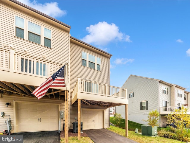 view of front of house with central air condition unit, a balcony, and a garage