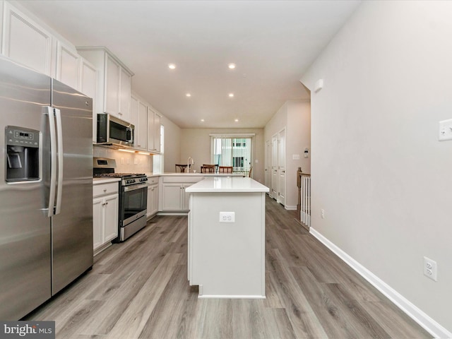 kitchen with white cabinetry, a kitchen island, stainless steel appliances, and light hardwood / wood-style floors