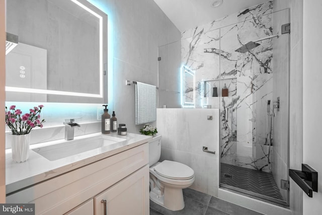 bathroom with an enclosed shower, vanity, tile walls, tile patterned flooring, and toilet