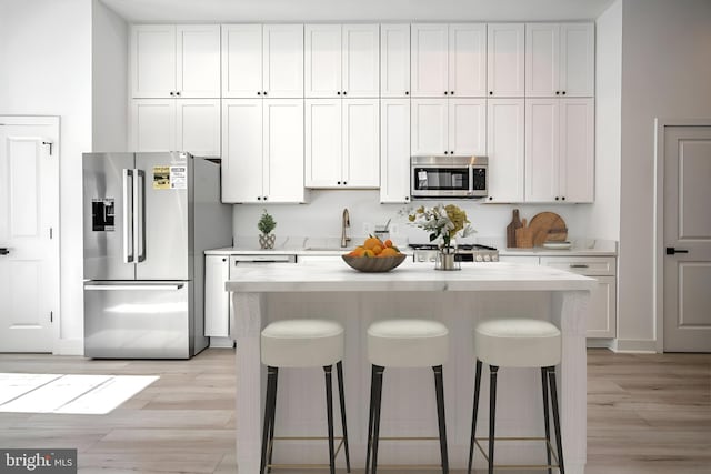 kitchen with a center island, stainless steel appliances, white cabinetry, and light hardwood / wood-style floors