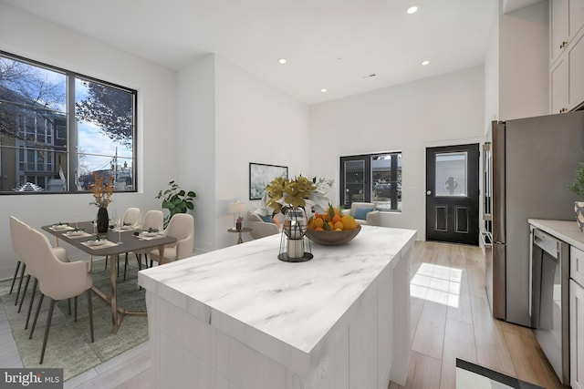 kitchen featuring a kitchen island, white cabinetry, appliances with stainless steel finishes, and light hardwood / wood-style flooring