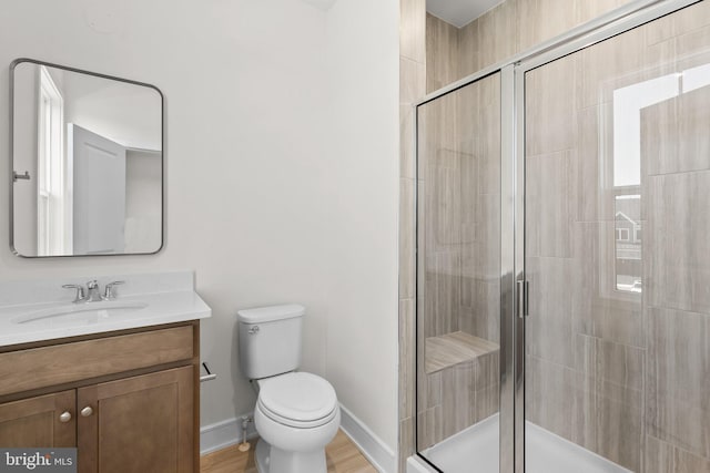 bathroom featuring hardwood / wood-style flooring, vanity, toilet, and a shower with door