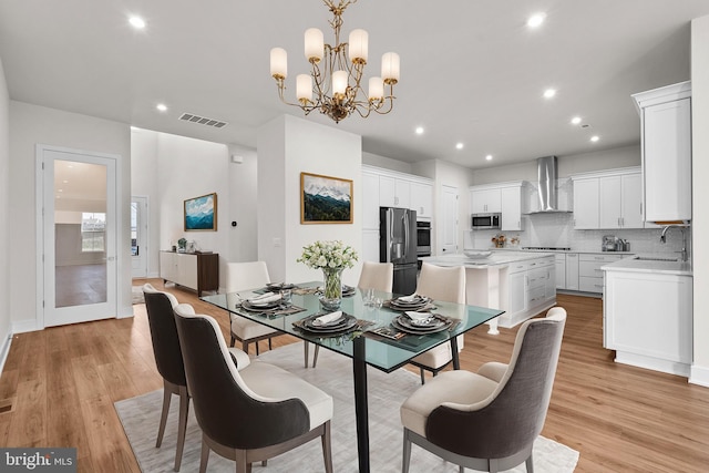 dining area featuring a chandelier, light wood-type flooring, and sink