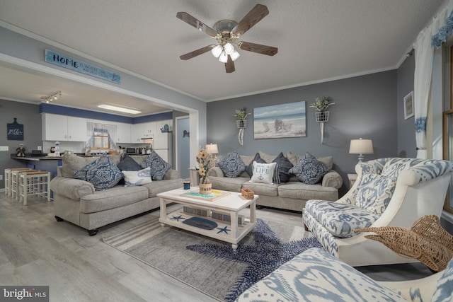 living room featuring a textured ceiling, ceiling fan, crown molding, and light hardwood / wood-style flooring