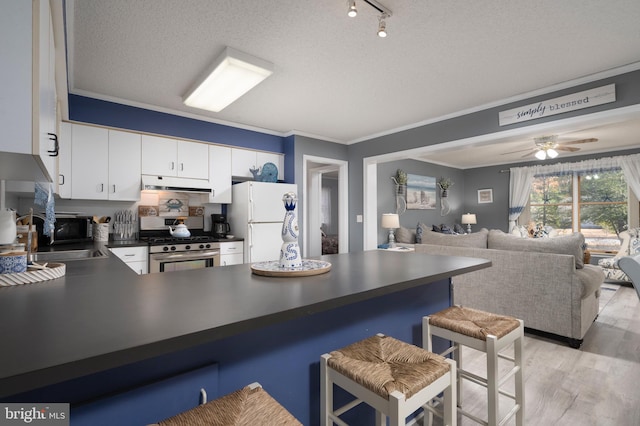 kitchen with appliances with stainless steel finishes, light wood-type flooring, a kitchen breakfast bar, crown molding, and white cabinets