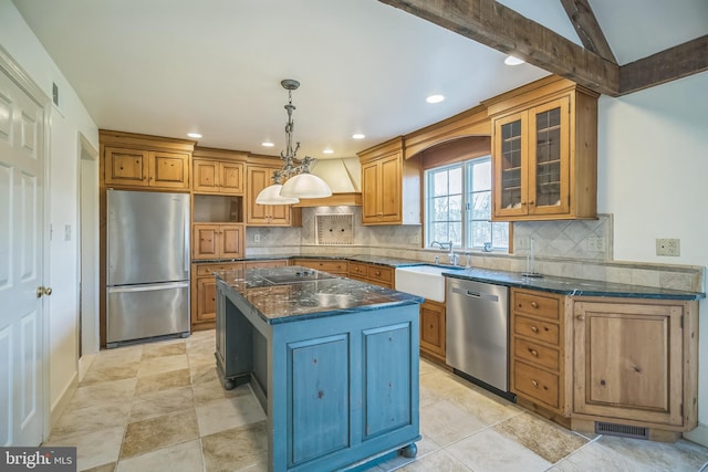 kitchen with decorative backsplash, appliances with stainless steel finishes, sink, dark stone countertops, and a center island