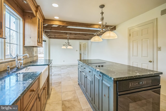 kitchen featuring a center island, beamed ceiling, dark stone counters, decorative light fixtures, and black appliances