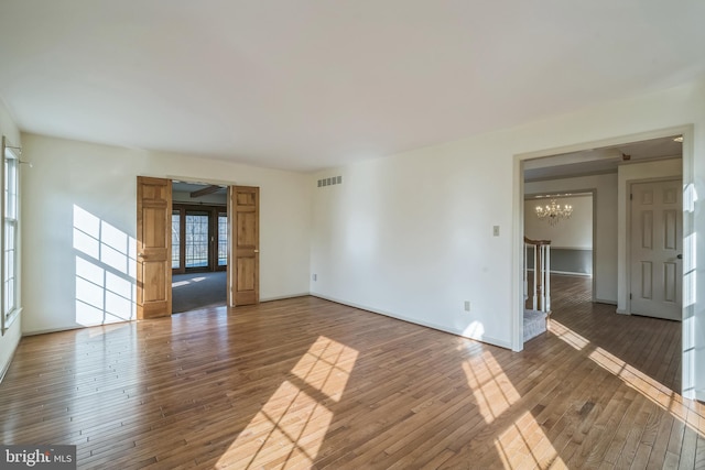 unfurnished room with a chandelier and hardwood / wood-style flooring