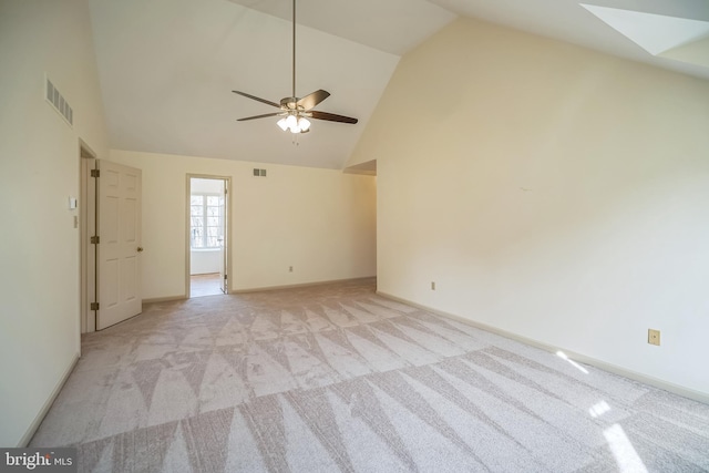 carpeted empty room featuring a skylight, ceiling fan, and high vaulted ceiling