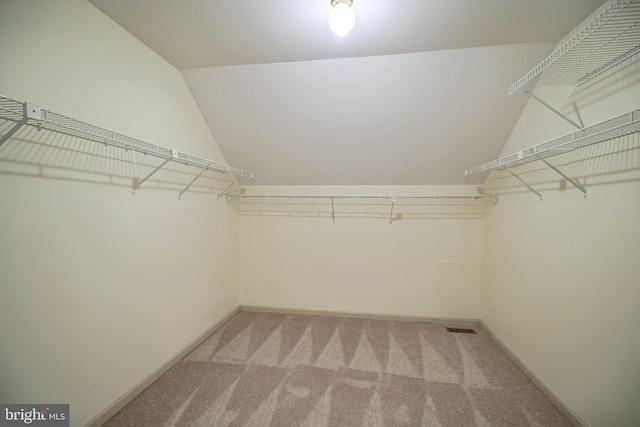 walk in closet featuring lofted ceiling and light carpet