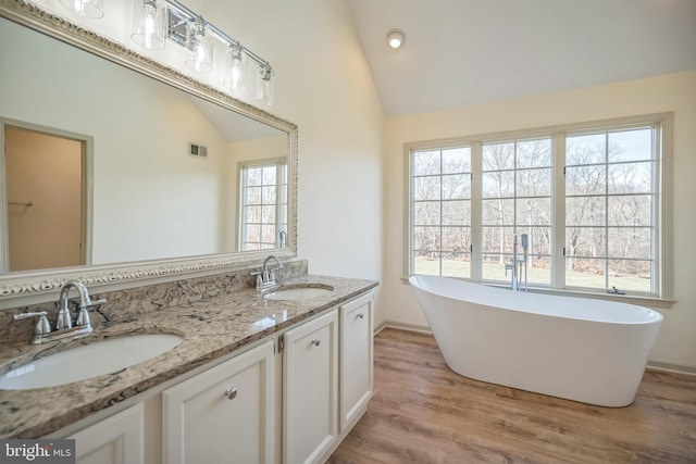 bathroom with a tub, a wealth of natural light, vaulted ceiling, and hardwood / wood-style flooring