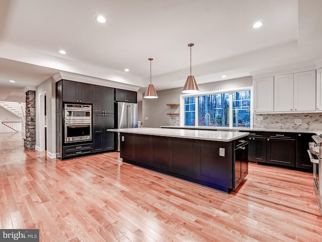 kitchen with a center island, light wood-type flooring, decorative light fixtures, and stainless steel appliances