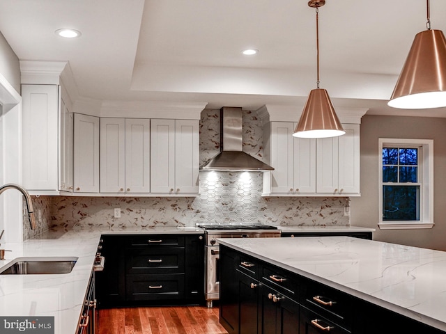 kitchen with sink, wall chimney exhaust hood, stainless steel stove, and decorative light fixtures