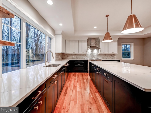 kitchen featuring pendant lighting, sink, wall chimney exhaust hood, and a healthy amount of sunlight