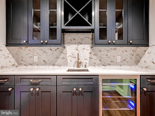 bar with decorative backsplash, light stone countertops, sink, and beverage cooler