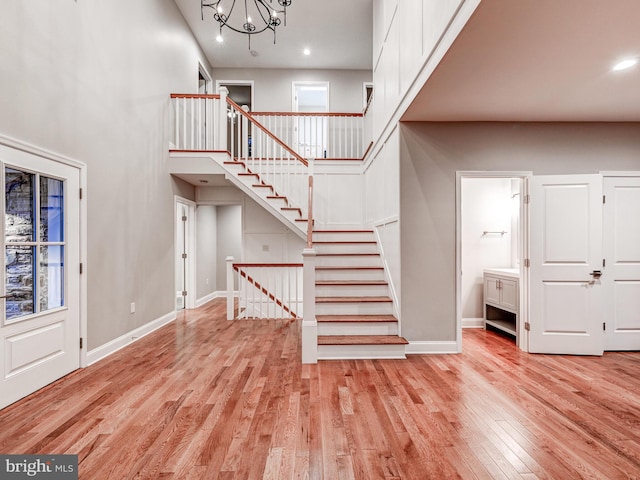 foyer with a chandelier, a towering ceiling, and light hardwood / wood-style floors