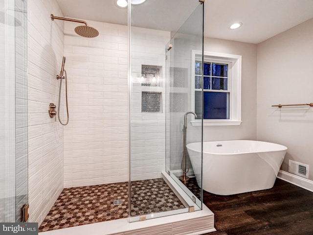 bathroom featuring wood-type flooring and plus walk in shower