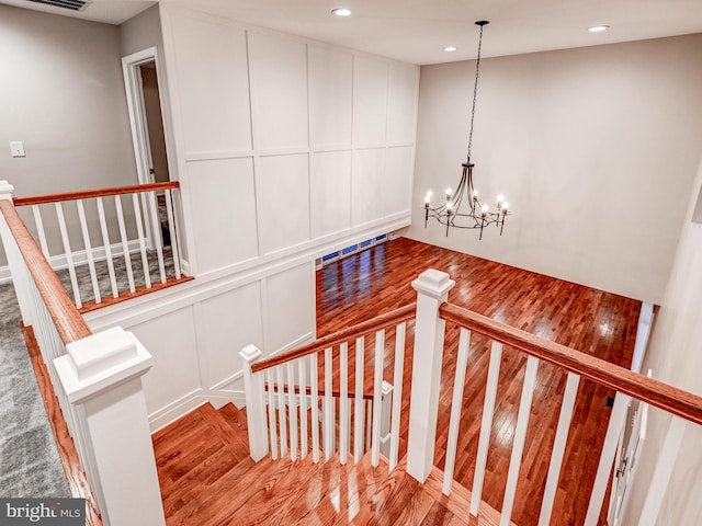 staircase featuring hardwood / wood-style floors and a notable chandelier