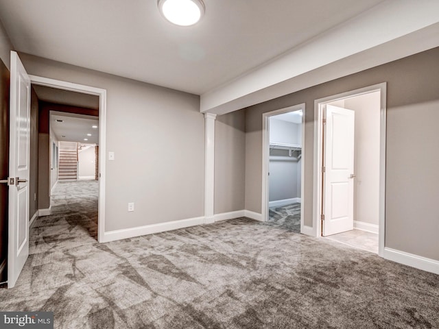 unfurnished bedroom featuring a walk in closet, a closet, and light colored carpet