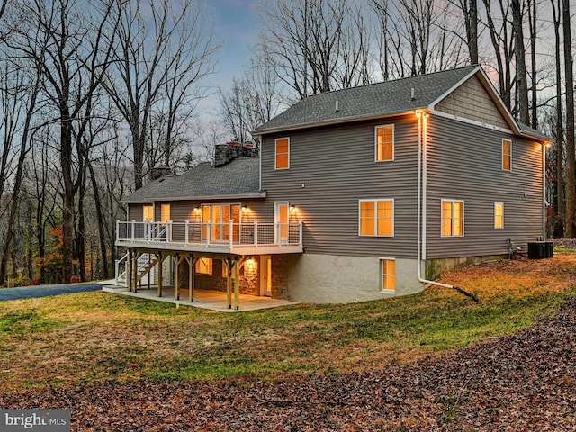 rear view of property with a patio, central AC, a wooden deck, and a lawn