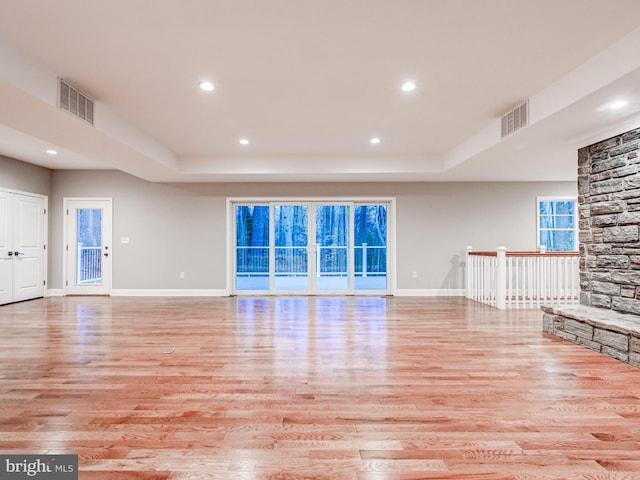 unfurnished living room featuring a tray ceiling, a fireplace, and light wood-type flooring