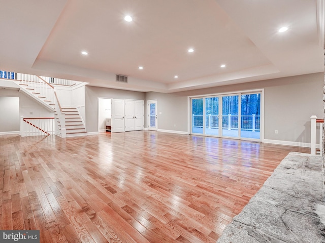 unfurnished living room featuring light hardwood / wood-style floors and a raised ceiling