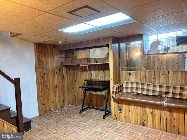 interior space featuring a drop ceiling and wood walls