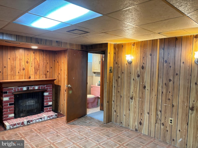 basement featuring wooden walls and a brick fireplace