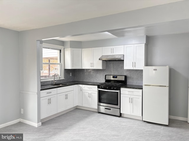 kitchen with decorative backsplash, stainless steel gas range, sink, white fridge, and white cabinetry