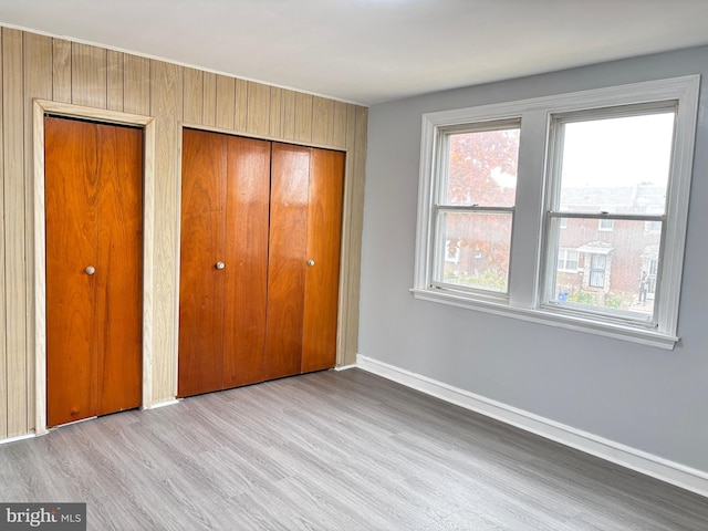 unfurnished bedroom featuring light hardwood / wood-style floors and two closets