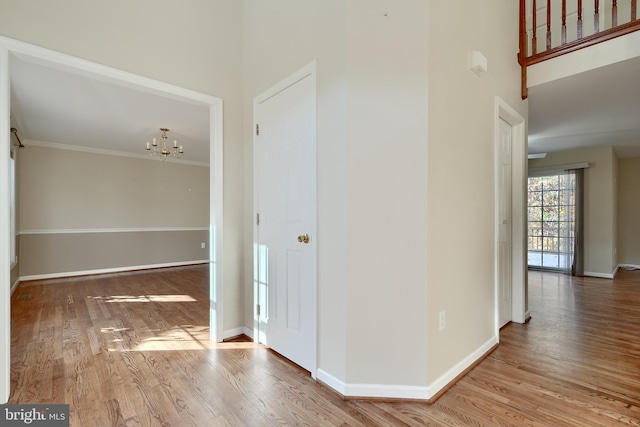 corridor featuring a chandelier, a high ceiling, hardwood / wood-style flooring, and ornamental molding