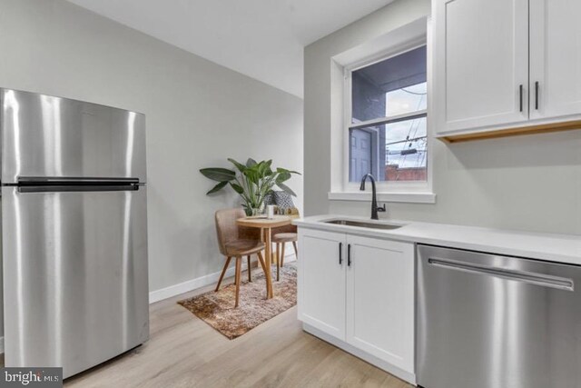 1645 Gorsuch Ave, Baltimore, MD 21218 - kitchen with stainless steel appliances, a sink, light wood-style flooring, light countertops, and white cabinets