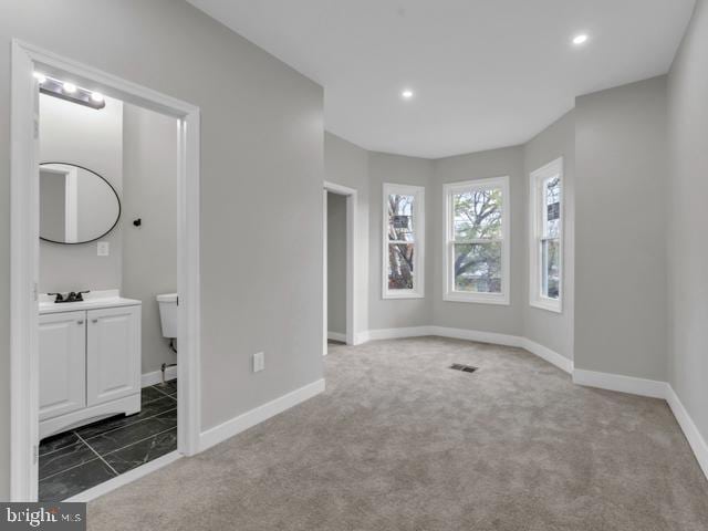 unfurnished bedroom featuring dark carpet and ensuite bath