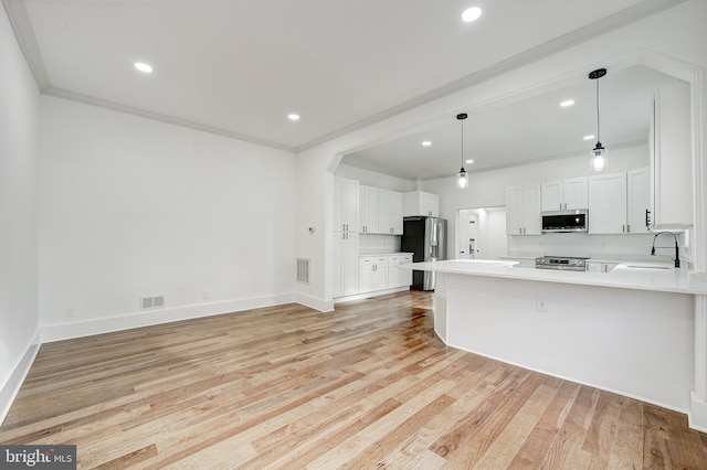 kitchen featuring white cabinetry, sink, pendant lighting, appliances with stainless steel finishes, and light wood-type flooring