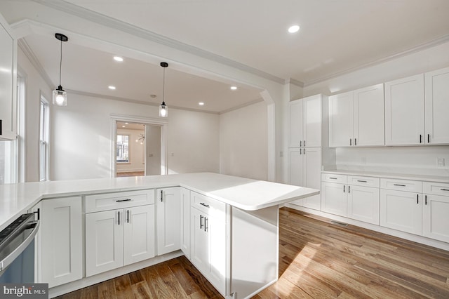 kitchen featuring kitchen peninsula, hardwood / wood-style floors, white cabinets, and hanging light fixtures