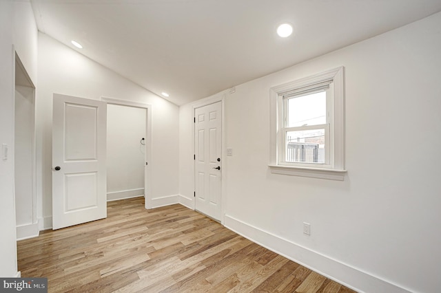 empty room with light hardwood / wood-style floors and vaulted ceiling