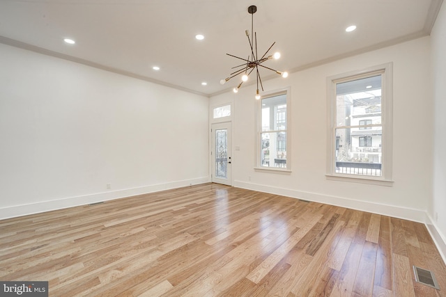 empty room featuring light wood-type flooring, crown molding, and an inviting chandelier