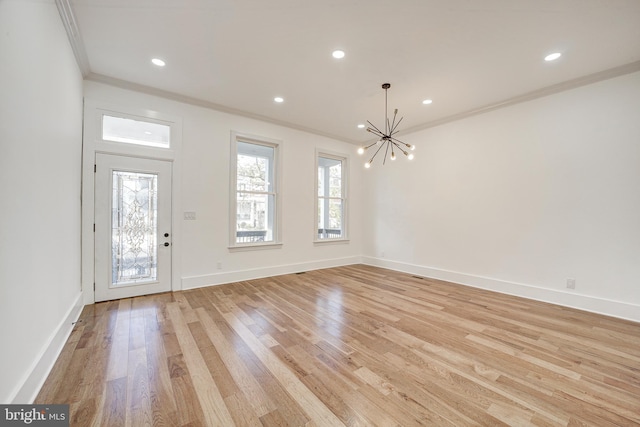 entrance foyer featuring light hardwood / wood-style floors, ornamental molding, and a chandelier