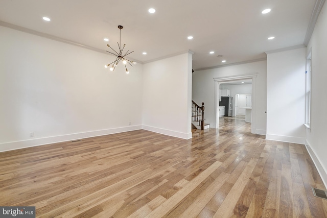 empty room featuring a notable chandelier, light wood-type flooring, and crown molding