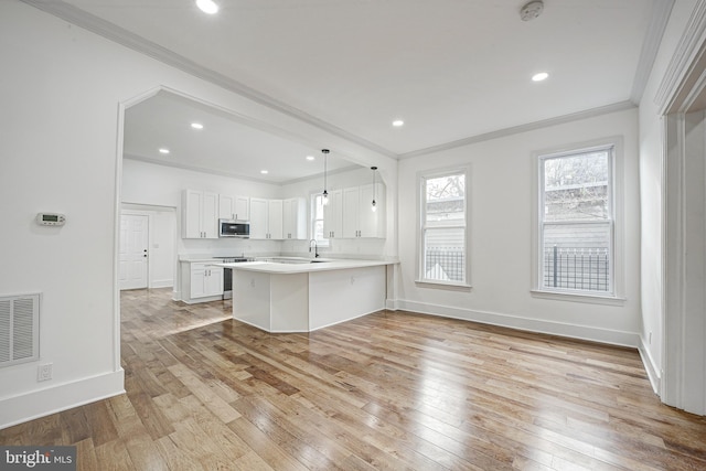 kitchen with hanging light fixtures, kitchen peninsula, light hardwood / wood-style flooring, appliances with stainless steel finishes, and white cabinetry