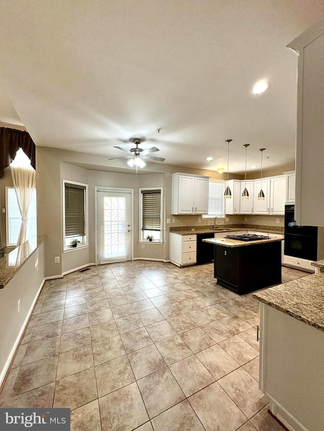 kitchen with sink, a center island, white cabinets, pendant lighting, and black appliances