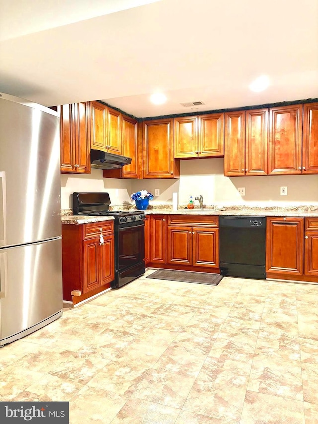 kitchen featuring light stone counters, sink, and black appliances