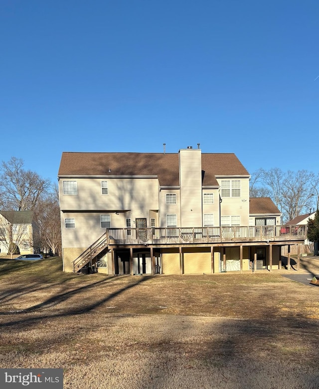 rear view of property featuring a wooden deck and a lawn