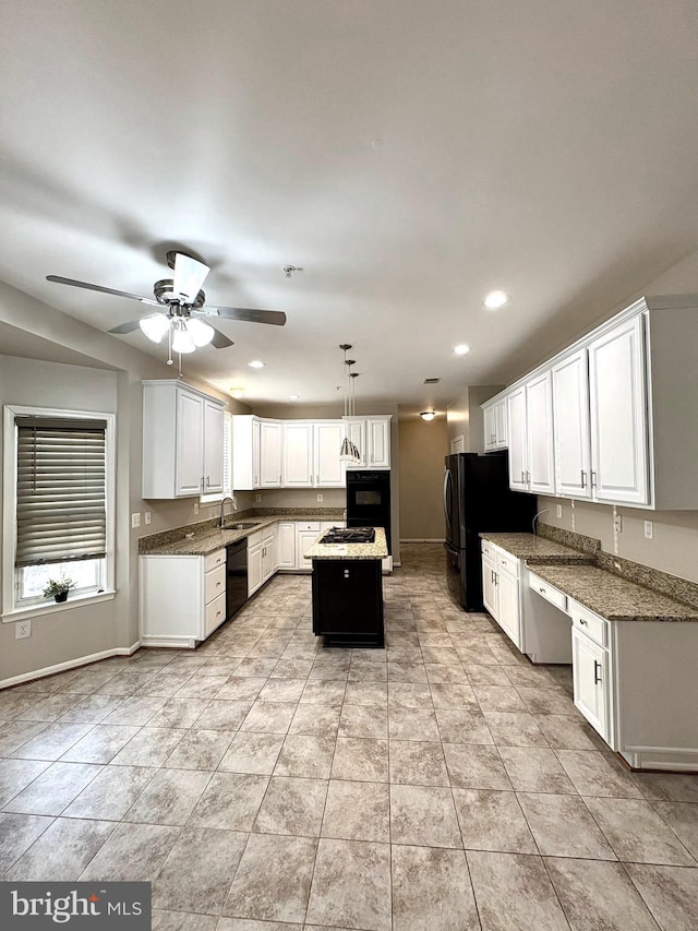 kitchen with built in desk, white cabinets, hanging light fixtures, a center island, and black appliances