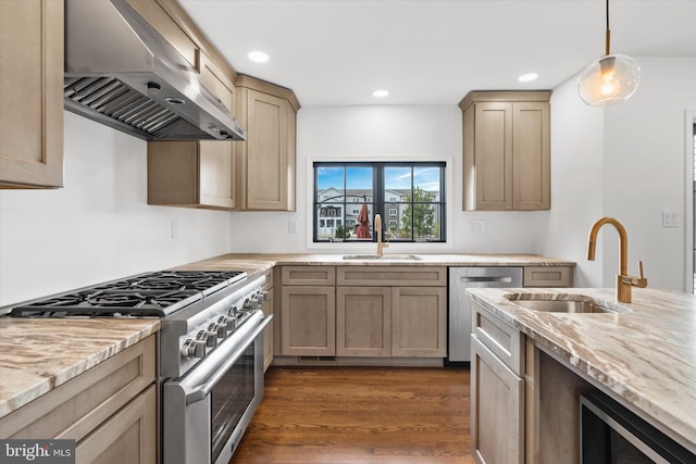 kitchen featuring sink, wall chimney exhaust hood, dark hardwood / wood-style floors, appliances with stainless steel finishes, and decorative light fixtures