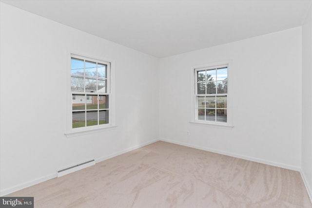 unfurnished room with light carpet, a baseboard radiator, and a wealth of natural light