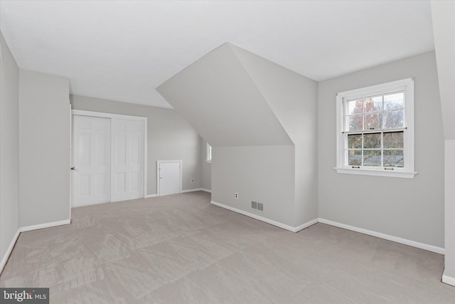 bonus room with light colored carpet and lofted ceiling