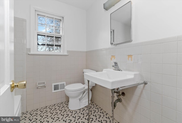 bathroom with a bathing tub, sink, tile patterned flooring, toilet, and tile walls