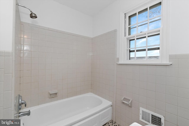 bathroom with tiled shower / bath combo and tile walls